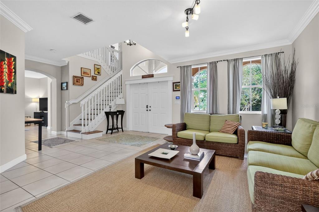 A living room with a staircase, tile and rug flooring, and wicker furniture — 15144 SW 20TH STREET, MIAMI, FL