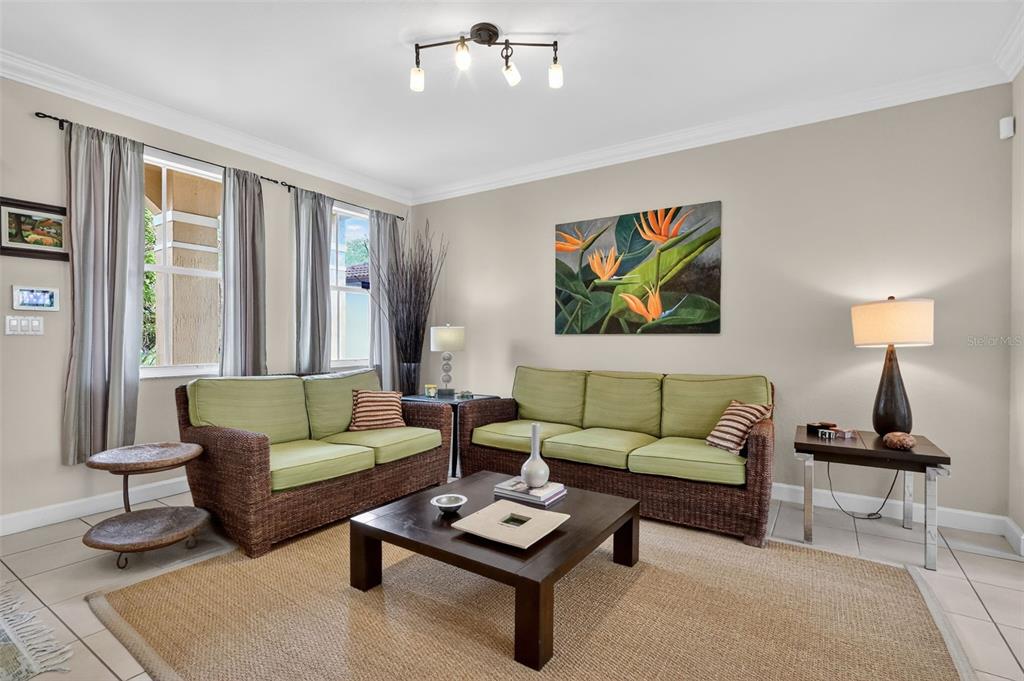A living room features wicker furniture with green cushions, a dark coffee table, and wall art — 15144 SW 20TH STREET, MIAMI, FL