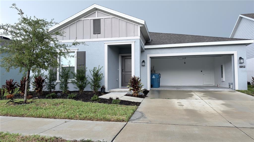 A single-story house with a light blue stucco exterior, a two-car garage, and front landscaping — 1129 DEEPWATER CIRCLE, EAGLE LAKE, FL