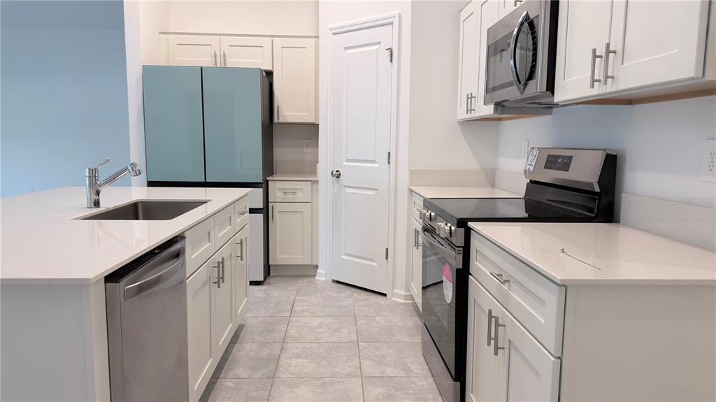 A kitchen features white cabinets, stainless steel appliances, a center island, and light-colored tile flooring — 1129 DEEPWATER CIRCLE, EAGLE LAKE, FL