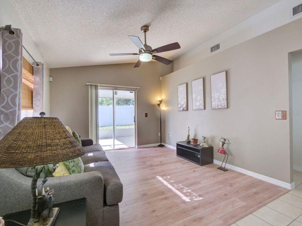 A living room with wood-look flooring, a ceiling fan, and sliding glass doors to a patio — 1012 VISTA PALMA WAY, ORLANDO, FL