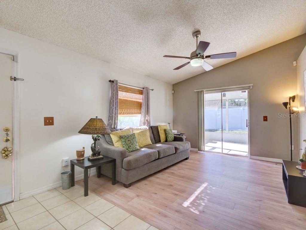 A living room features light wood flooring, a gray sofa, and a sliding glass door — 1012 VISTA PALMA WAY, ORLANDO, FL