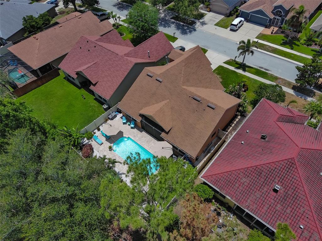 An aerial view shows a house with a brown roof, a swimming pool, and patio — 7613 NOTTINGHILL SKY DRIVE, APOLLO BEACH, FL