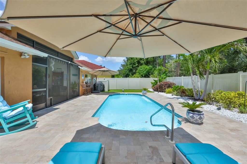 A backyard patio features a swimming pool, lounge chairs, and a large umbrella — 7613 NOTTINGHILL SKY DRIVE, APOLLO BEACH, FL