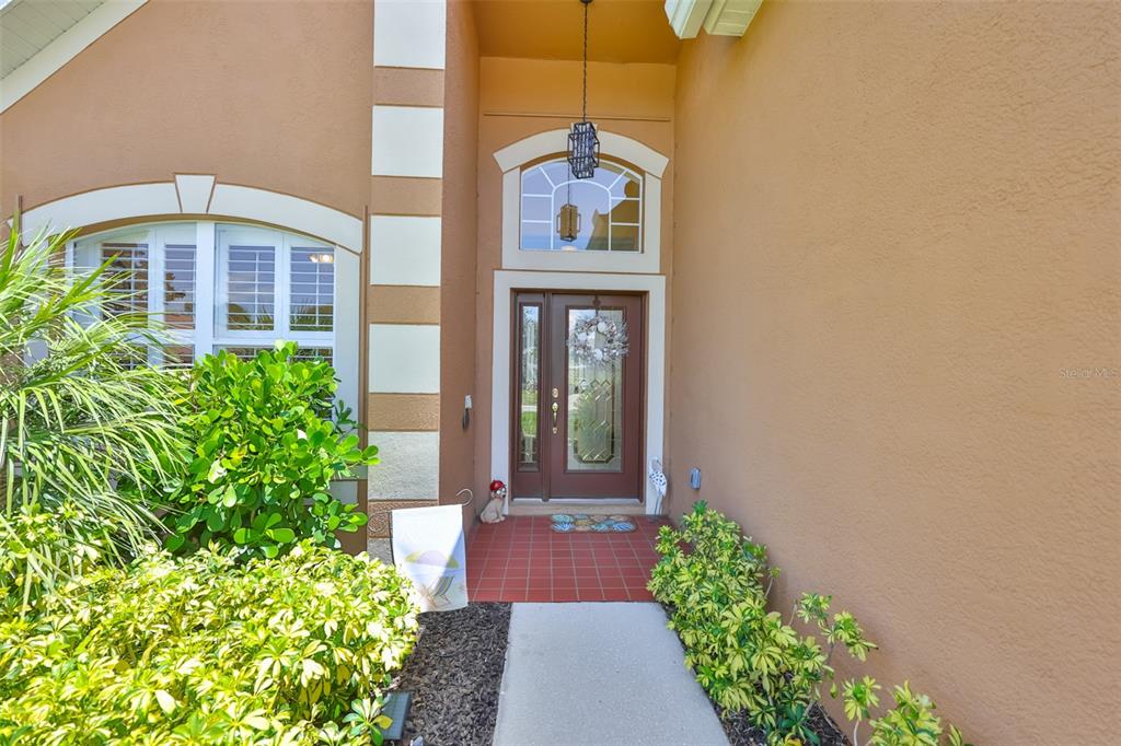 The front entrance of a house features a brown door with glass panels and sidelights — 7613 NOTTINGHILL SKY DRIVE, APOLLO BEACH, FL