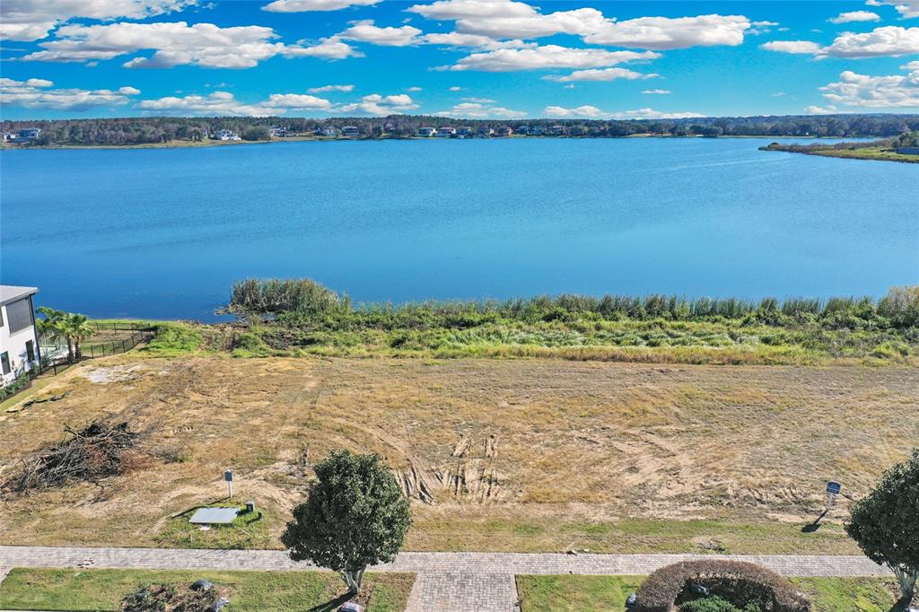An aerial view shows a vacant, grassy lot situated directly in front of a lake — 16626 BOLSENA DRIVE, BELLA COLLINA, FL