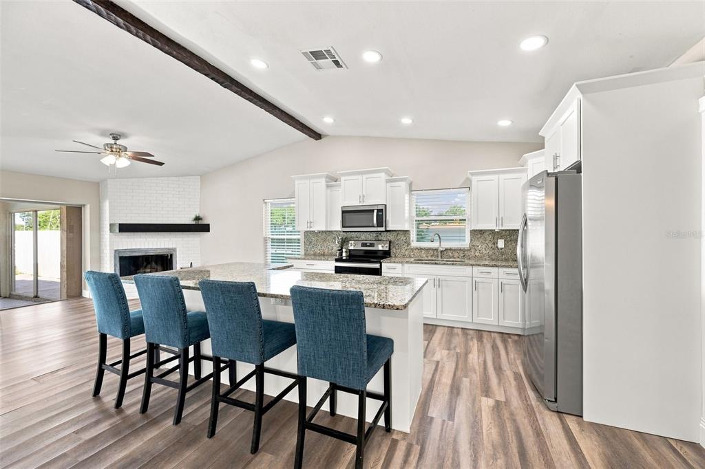 A kitchen with white cabinets, granite countertops, and a breakfast bar with four blue chairs — 3276 FOX HILL DRIVE, CLEARWATER, FL