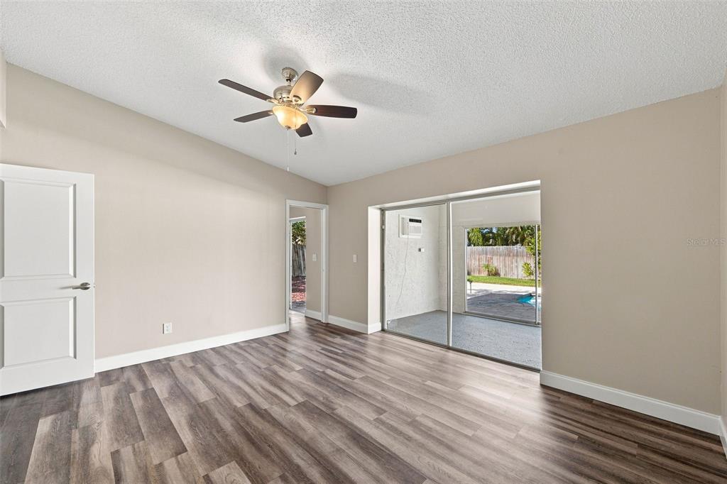 An empty room with wood-look flooring, a ceiling fan, and sliding doors to a patio — 3276 FOX HILL DRIVE, CLEARWATER, FL