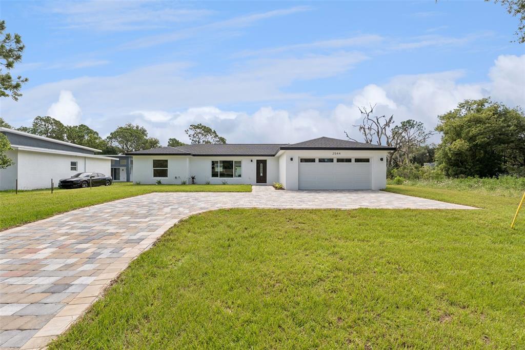 A white single-story house with a paved driveway and a two-car garage — 2544 N ARROWHEAD ROAD, AVON PARK, FL