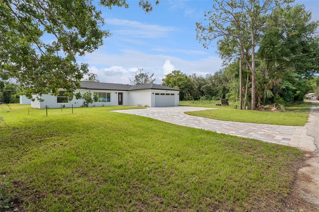 A bright, open-concept living area features white marble-look tile flooring and a dark front door — 2544 N ARROWHEAD ROAD, AVON PARK, FL