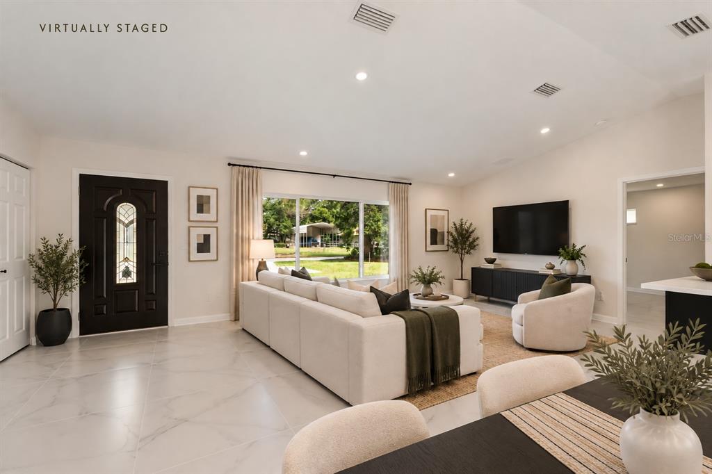 A modern open-concept kitchen and living area with white marble-look tile floors and dark cabinetry — 2544 N ARROWHEAD ROAD, AVON PARK, FL