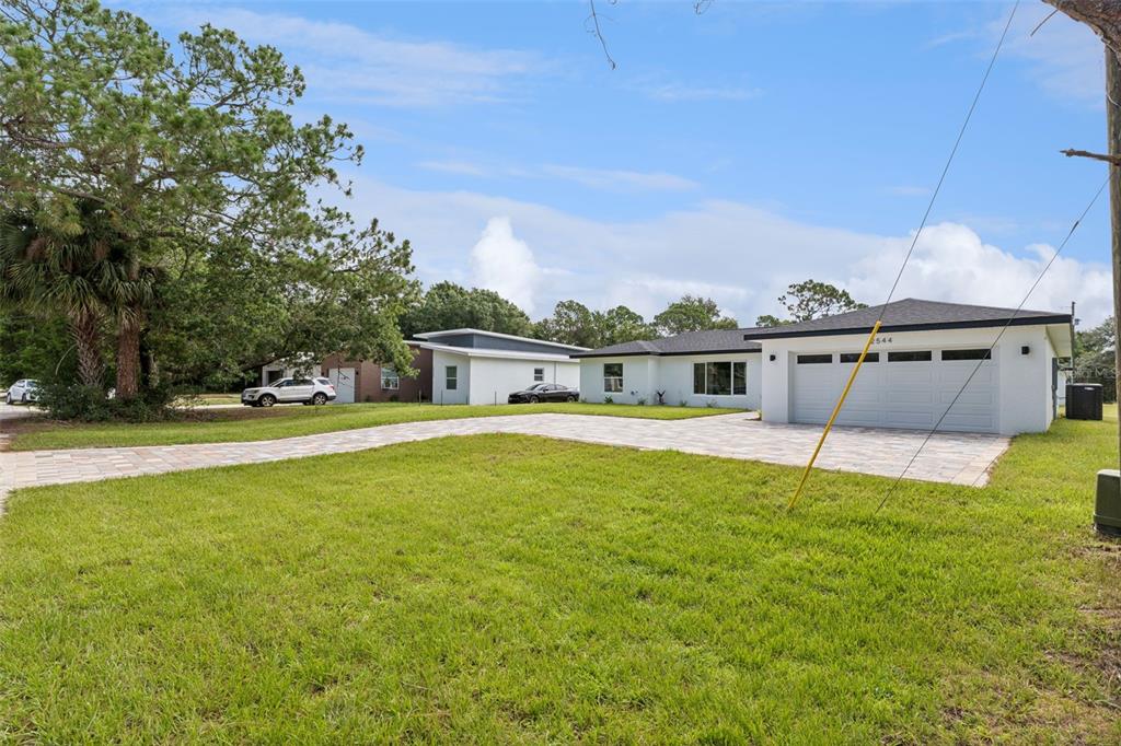 A modern open-concept kitchen and living area with white marble-look tile floors and dark cabinetry — 2544 N ARROWHEAD ROAD, AVON PARK, FL