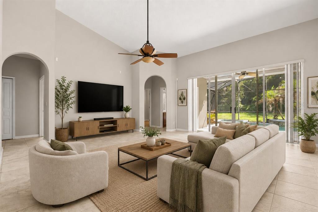 A living room with a vaulted ceiling, beige tile floors, a sectional sofa, and sliding doors — 3451 PLAYERS POINT LOOP, APOPKA, FL