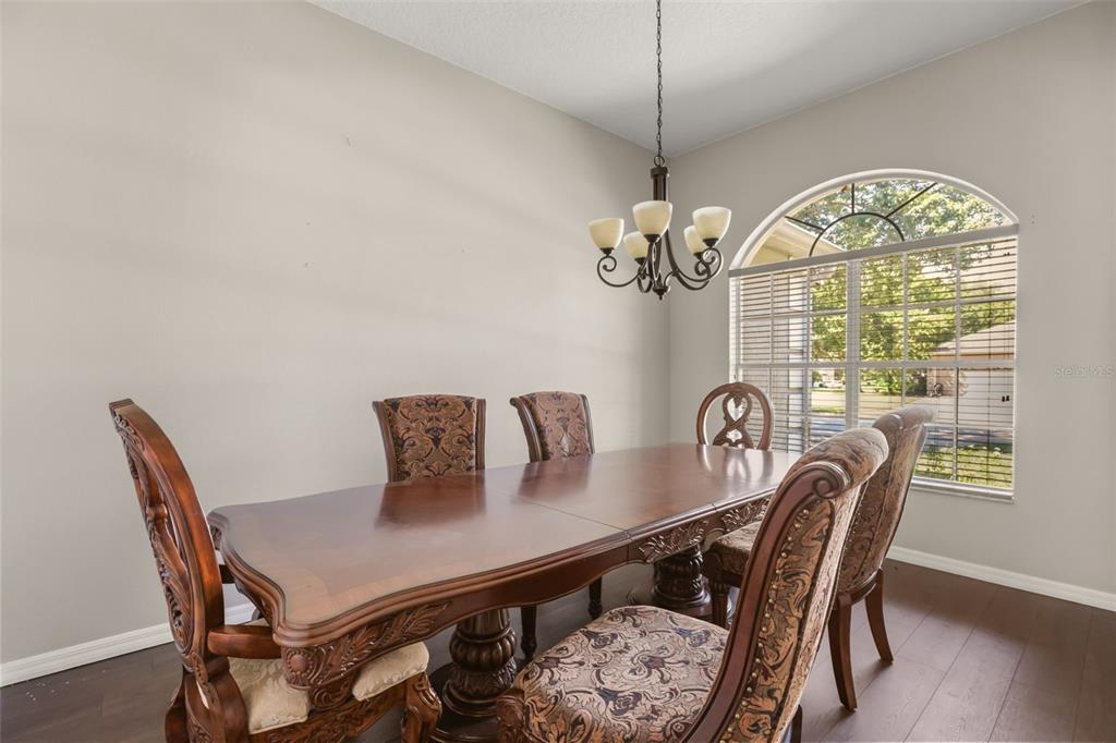 A dining room features a wooden table, upholstered chairs, a chandelier, and an arched window — 3451 PLAYERS POINT LOOP, APOPKA, FL