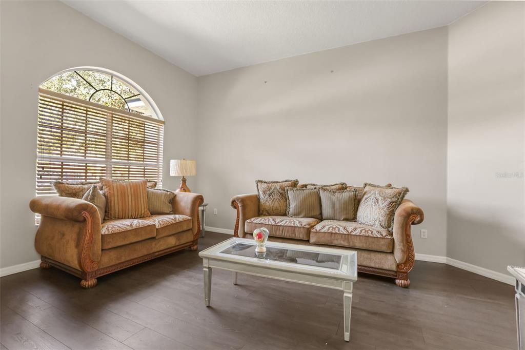 A living room features two brown sofas, a glass-topped coffee table, and an arched window — 3451 PLAYERS POINT LOOP, APOPKA, FL