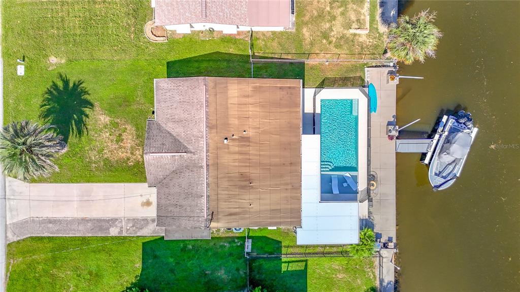 An aerial view of a waterfront house with a swimming pool and a docked boat — 7629 HATTERAS DRIVE, HUDSON, FL