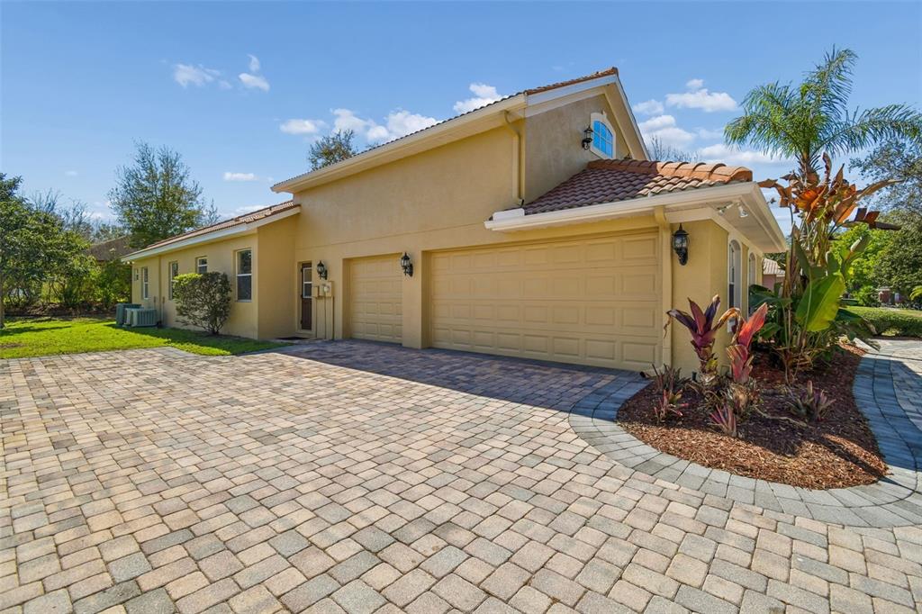 A tan house with a three-car garage and a paved driveway under a blue sky — 614 VINTAGE WAY, BRANDON, FL