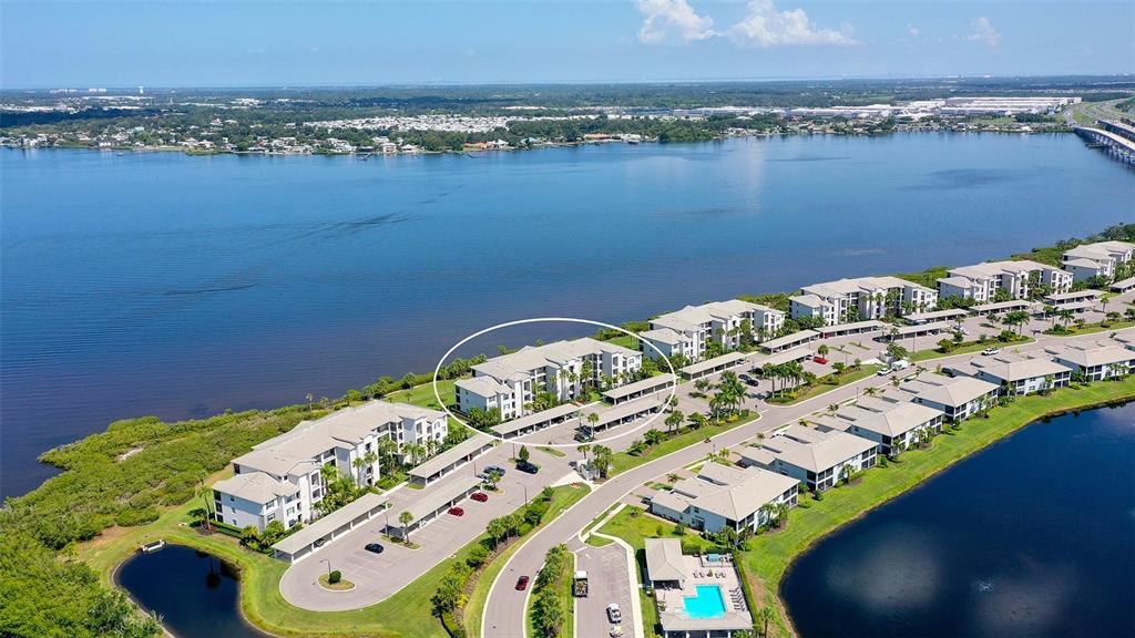 An aerial view shows a multi-story apartment building circled within a waterfront residential complex — 910 TIDEWATER SHORES LOOP UNIT 402, BRADENTON, FL
