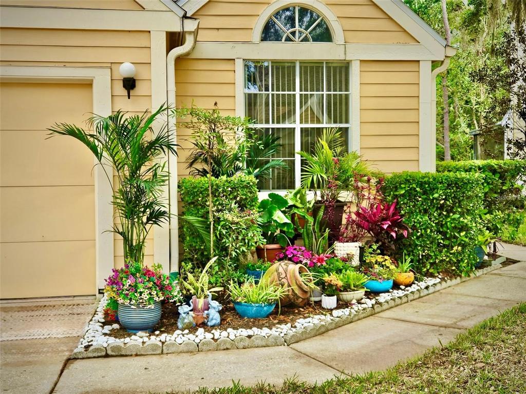 A garden bed with various potted plants and flowers sits in front of a house — 3612 PINE KNOT DRIVE, VALRICO, FL