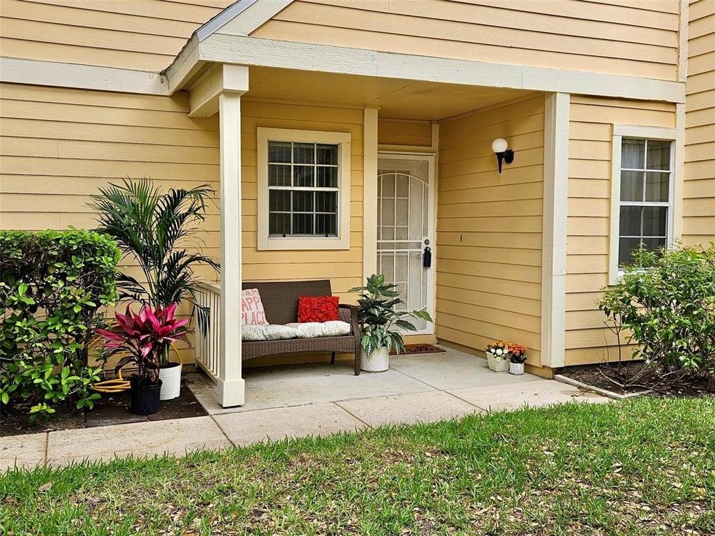 A covered concrete patio features a small bench, potted plants, and a screen door — 3612 PINE KNOT DRIVE, VALRICO, FL
