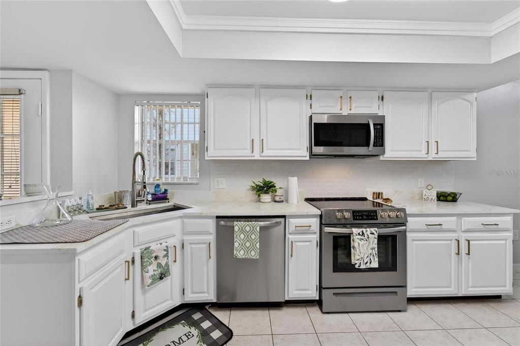 A kitchen with white cabinets, stainless steel appliances, and light-colored countertops — 3612 PINE KNOT DRIVE, VALRICO, FL