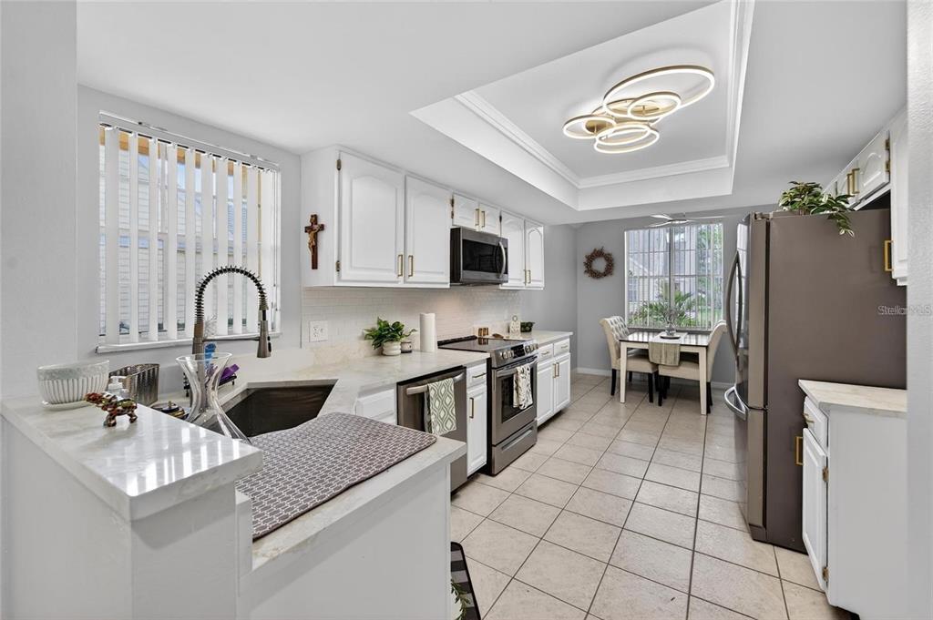 A kitchen with white cabinets, stainless steel appliances, and a dining area by a window — 3612 PINE KNOT DRIVE, VALRICO, FL