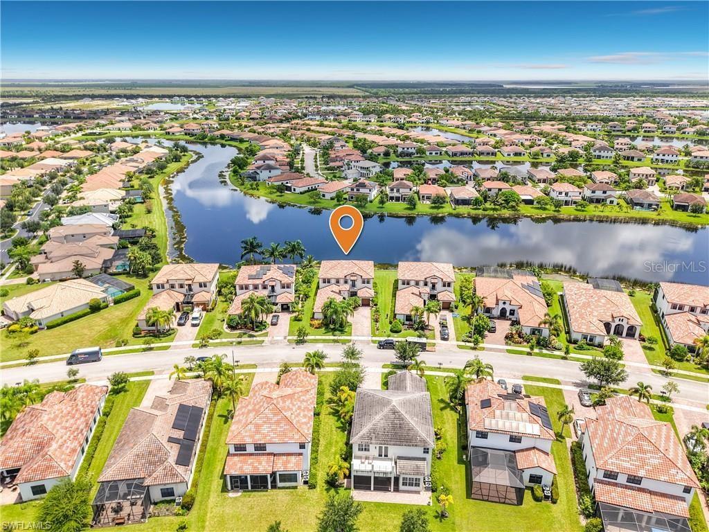 An aerial view shows a residential neighborhood with houses surrounding a central lake — 5024 MILANO STREET, AVE MARIA, FL