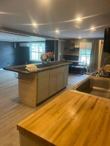 A kitchen features a wooden countertop, a central island with gray cabinets, and light flooring — 7890 MARX DRIVE, NORTH FORT MYERS, FL
