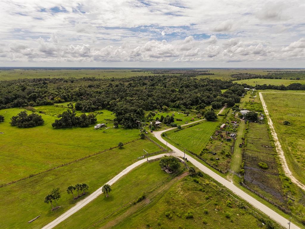 An aerial view of a rural property featuring a gravel road, pastures, and wooded areas — 16501 COKER GULLY ROAD, MYAKKA CITY, FL