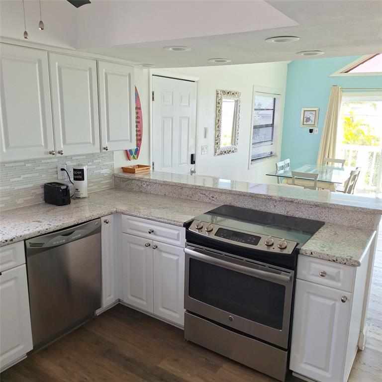 A kitchen with white cabinets, granite countertops, stainless steel appliances, and a breakfast bar — 13202 GULF BOULEVARD, MADEIRA BEACH, FL