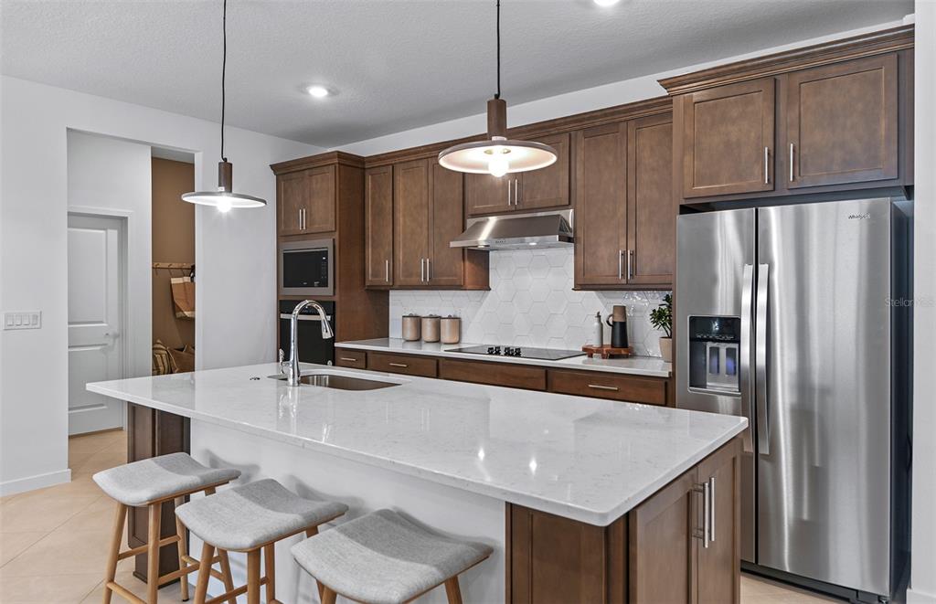 A kitchen features a large white quartz island, dark wood cabinets, and stainless steel appliances — 3656 OBSIDIAN DRIVE, SPRING HILL, FL