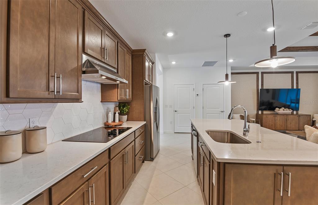 A kitchen features wood cabinets, white countertops, a tile backsplash, and a large center island — 3656 OBSIDIAN DRIVE, SPRING HILL, FL