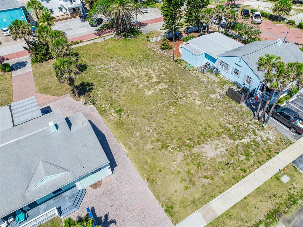 An aerial view shows a vacant rectangular lot situated between two existing residential buildings — 118 N ATLANTIC, COCOA BEACH, FL