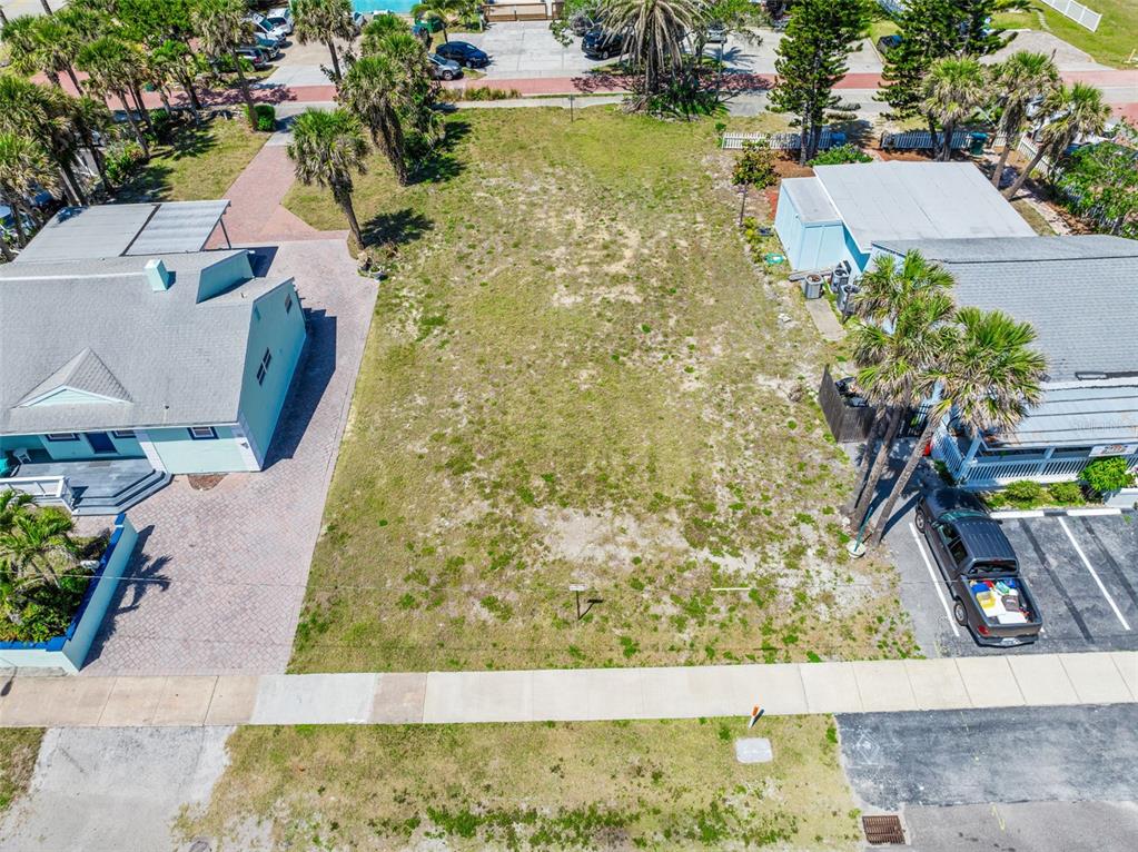 An aerial view shows a vacant rectangular lot situated between two houses and palm trees — 118 N ATLANTIC, COCOA BEACH, FL