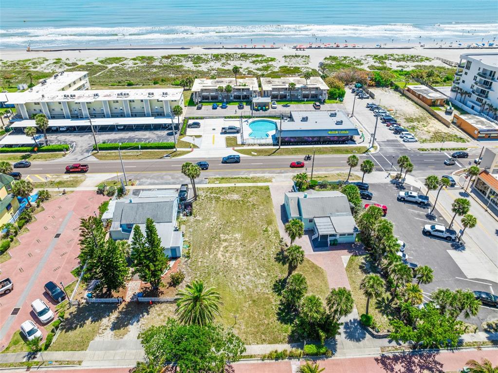 An aerial view shows two small houses separated by a vacant lot near the beach — 118 N ATLANTIC, COCOA BEACH, FL