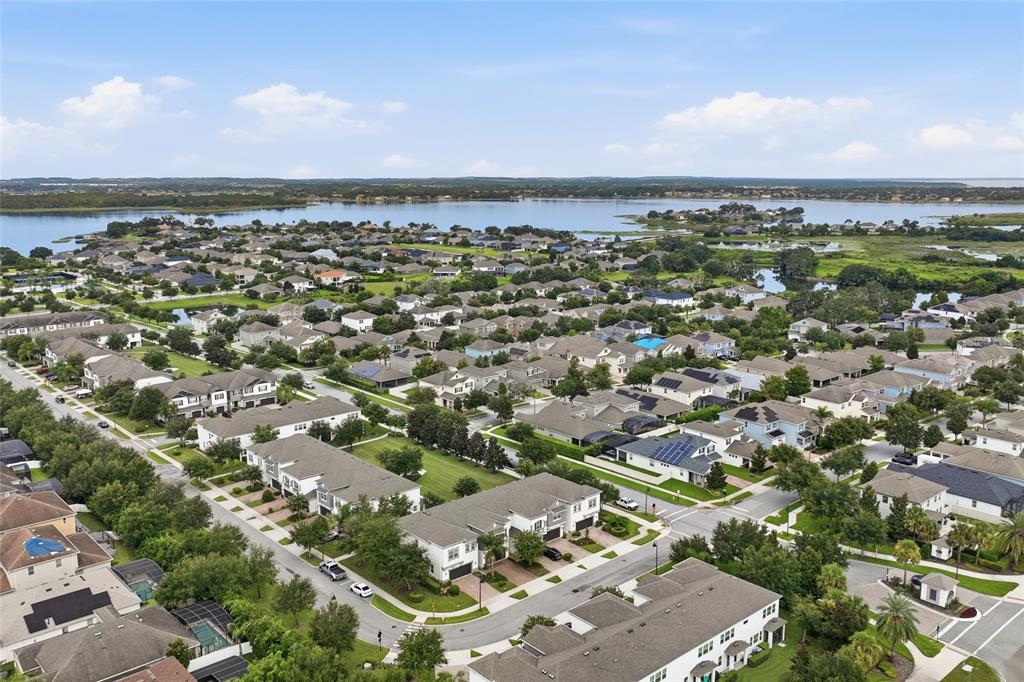 An aerial view shows a suburban neighborhood with many houses near a large lake — 15613 ORANGE HARVEST LOOP, WINTER GARDEN, FL