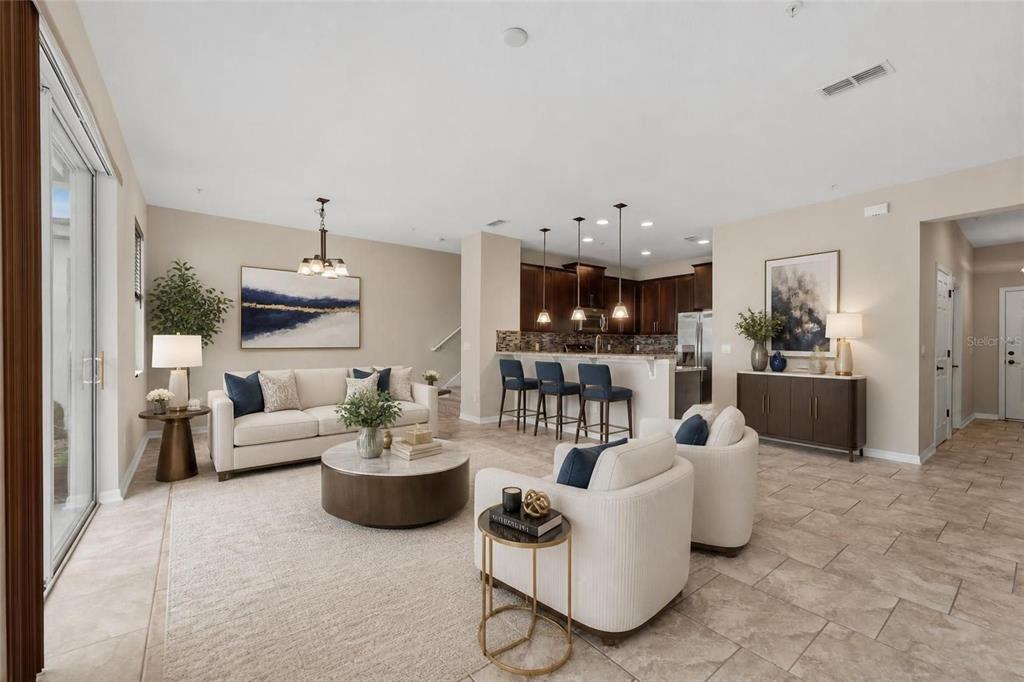 An open-concept living room and kitchen featuring tile floors, neutral furniture, and dark wood cabinetry — 15613 ORANGE HARVEST LOOP, WINTER GARDEN, FL