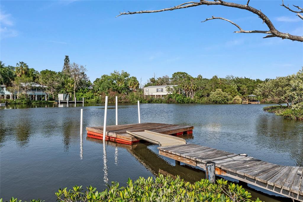 A wooden floating dock extends into a calm waterway surrounded by trees and houses — 1326 S ESTUARY, CRYSTAL RIVER, FL