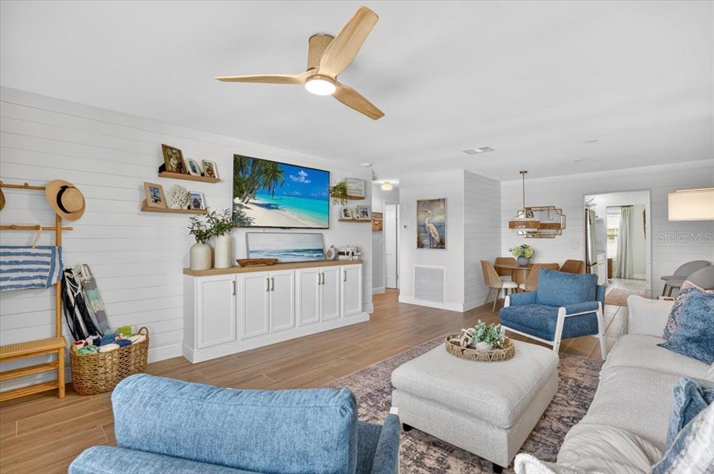 A bright living room features shiplap walls, a ceiling fan, and blue accent furniture — 2960 59TH STREET S UNIT 310, GULFPORT, FL