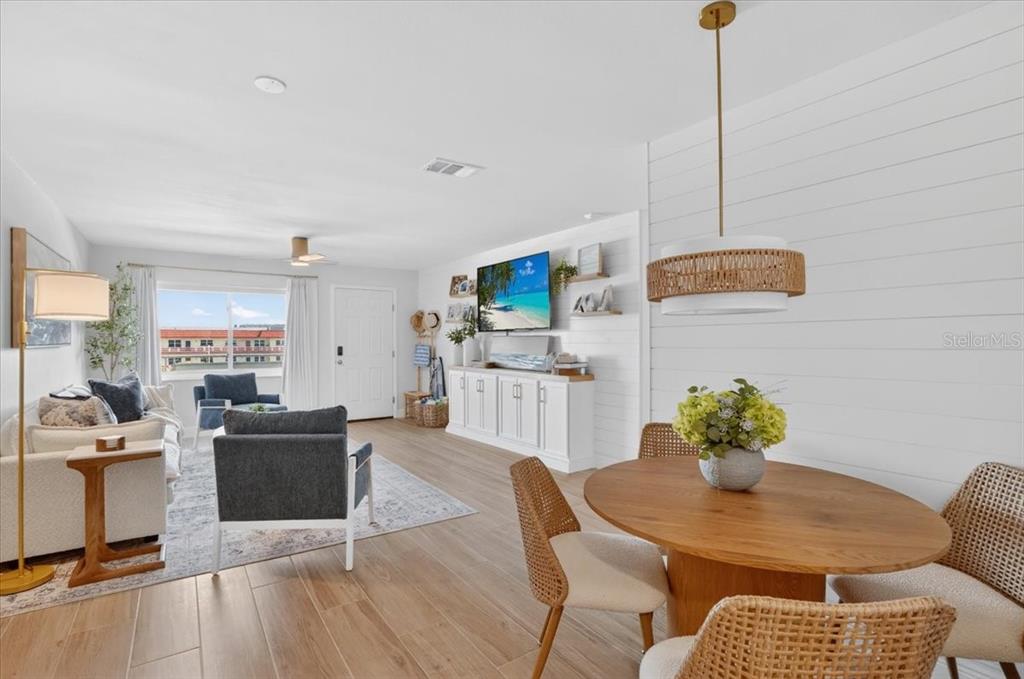 A bright open-concept living and dining area features wood-look flooring and a shiplap accent wall — 2960 59TH STREET S UNIT 310, GULFPORT, FL