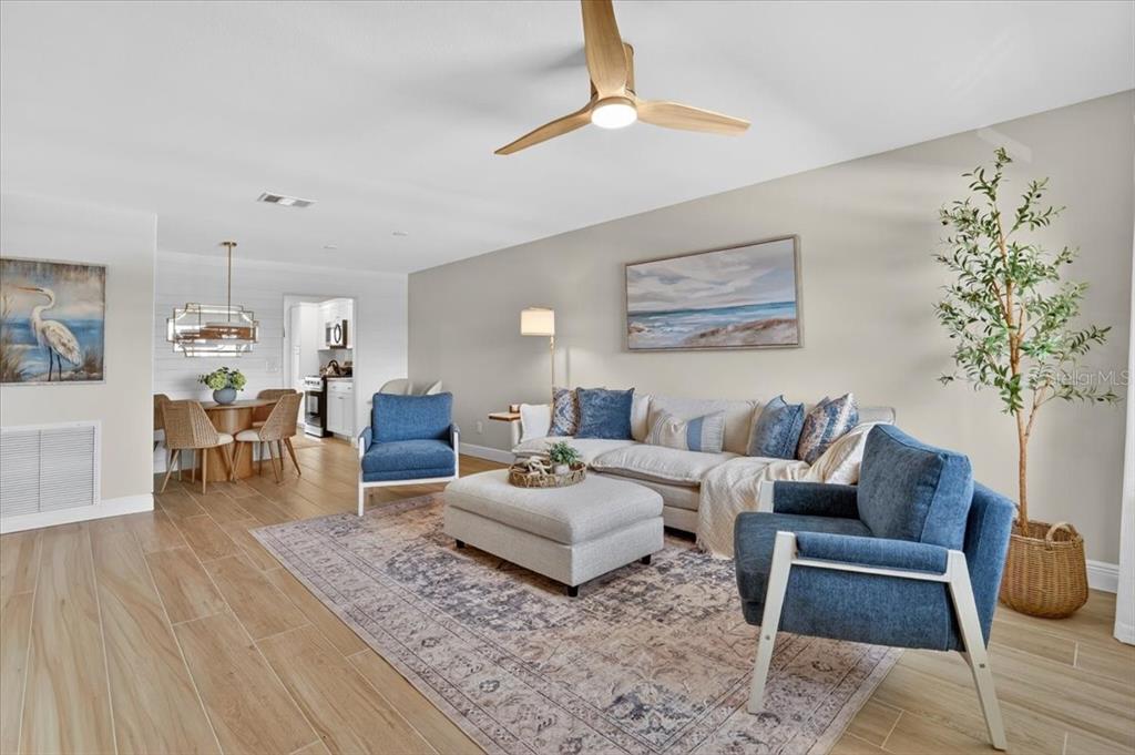 A living room with a sectional sofa, two blue armchairs, and a dining area — 2960 59TH STREET S UNIT 310, GULFPORT, FL