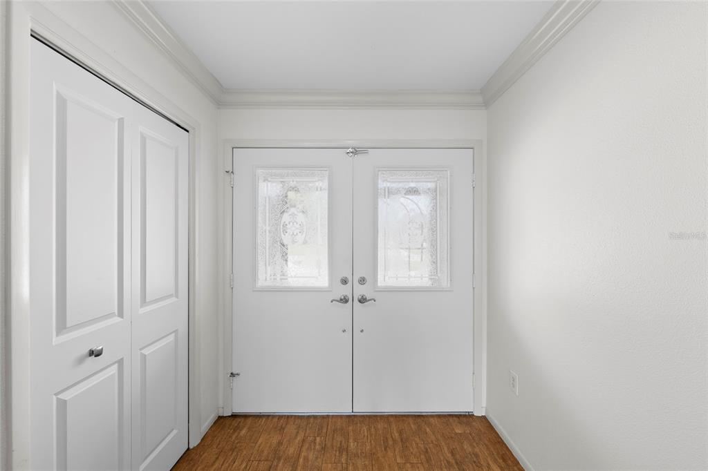 An entryway features white double doors with glass inserts, a closet, and wood-look flooring — 1252 WATERSIDE LANE, VENICE, FL