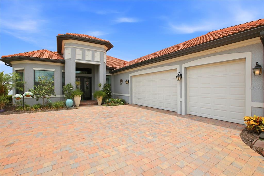 A house exterior features a paver driveway, a three-car garage, and a tiled roof — 617 MARAVIYA BOULEVARD, NOKOMIS, FL