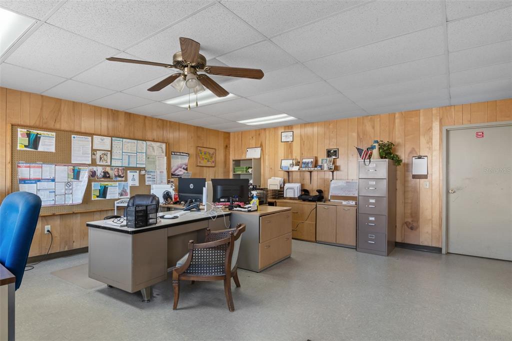 An office space features wood-paneled walls, a drop ceiling with a fan, and a metal desk — 6331 & 6275 S TEX POINT, HOMOSASSA, FL