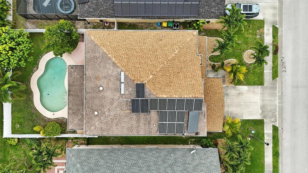 An aerial view shows a house with a shingled roof, solar panels, and a pool — 10043 WINDING RIVER ROAD, PUNTA GORDA, FL