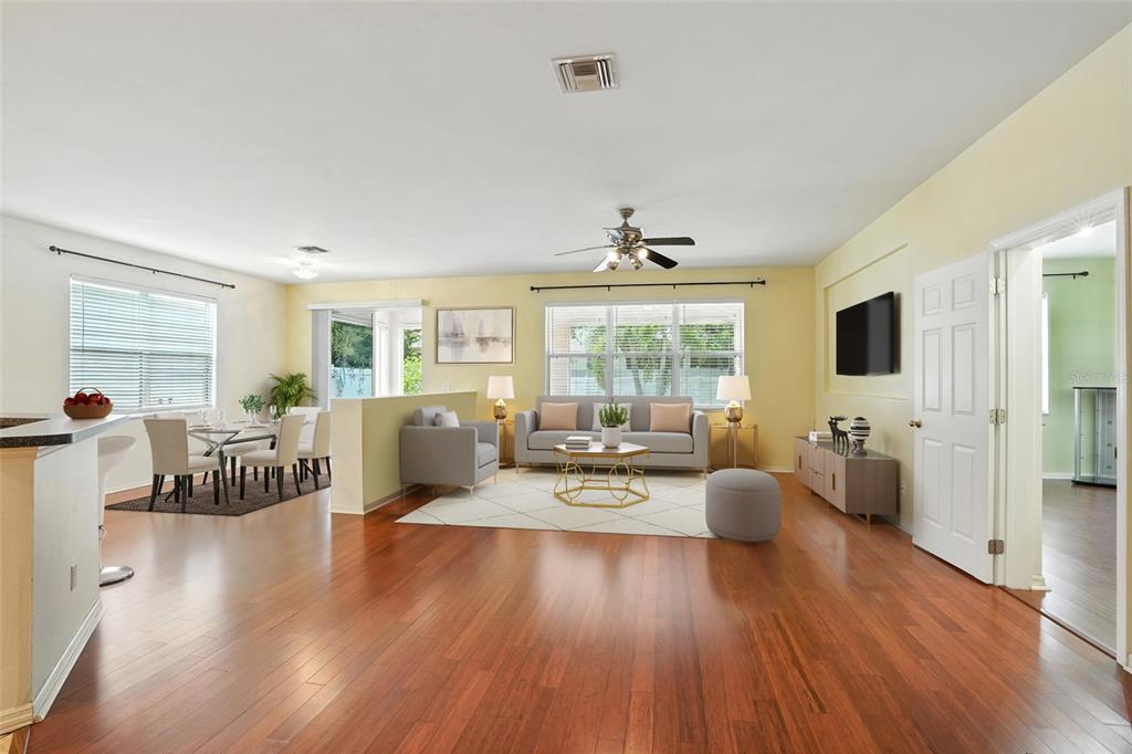 A living and dining area with hardwood floors, yellow walls, and a ceiling fan — 10043 WINDING RIVER ROAD, PUNTA GORDA, FL