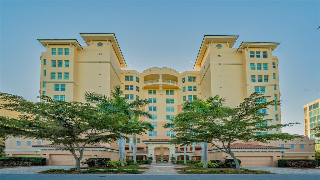 A multi-story yellow apartment building with palm trees and a central entrance fountain — 401 N POINT ROAD UNIT 603, OSPREY, FL