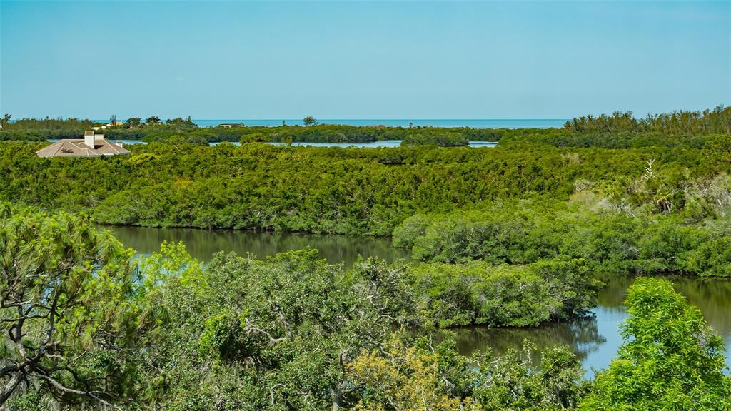 An elevated view of a coastal landscape featuring dense green mangroves, a waterway, and ocean — 401 N POINT ROAD UNIT 603, OSPREY, FL