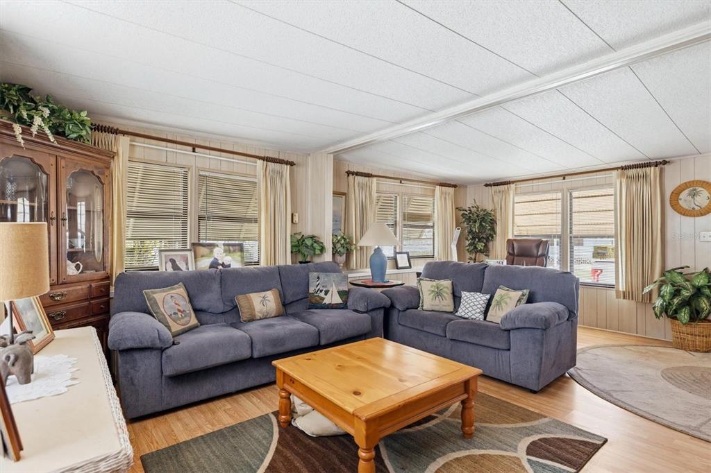 A living room features two blue sofas, a wooden coffee table, and light wood flooring — 4109 12TH STREET E, ELLENTON, FL