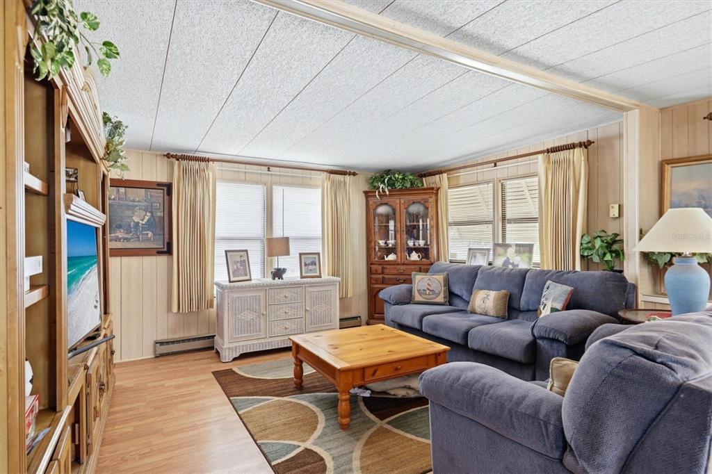A living room features wood-paneled walls, a blue sofa, a coffee table, and a television — 4109 12TH STREET E, ELLENTON, FL